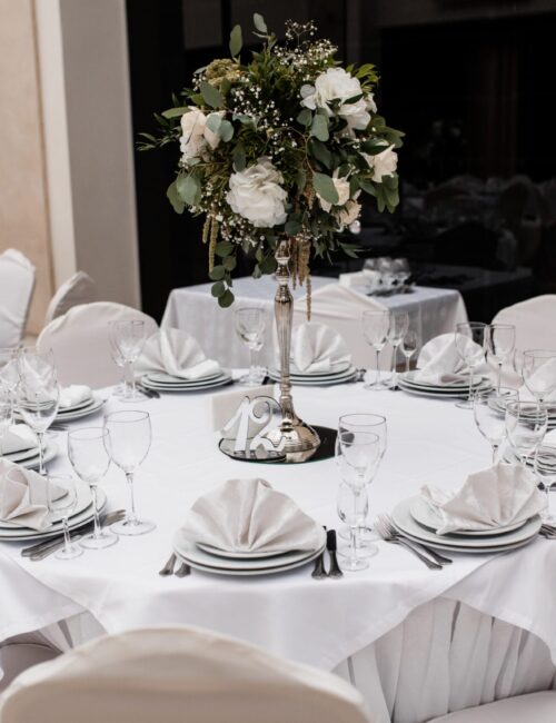 podawany w restauracji bialy okragly stol z kwiatowym elementem centralnym scaled